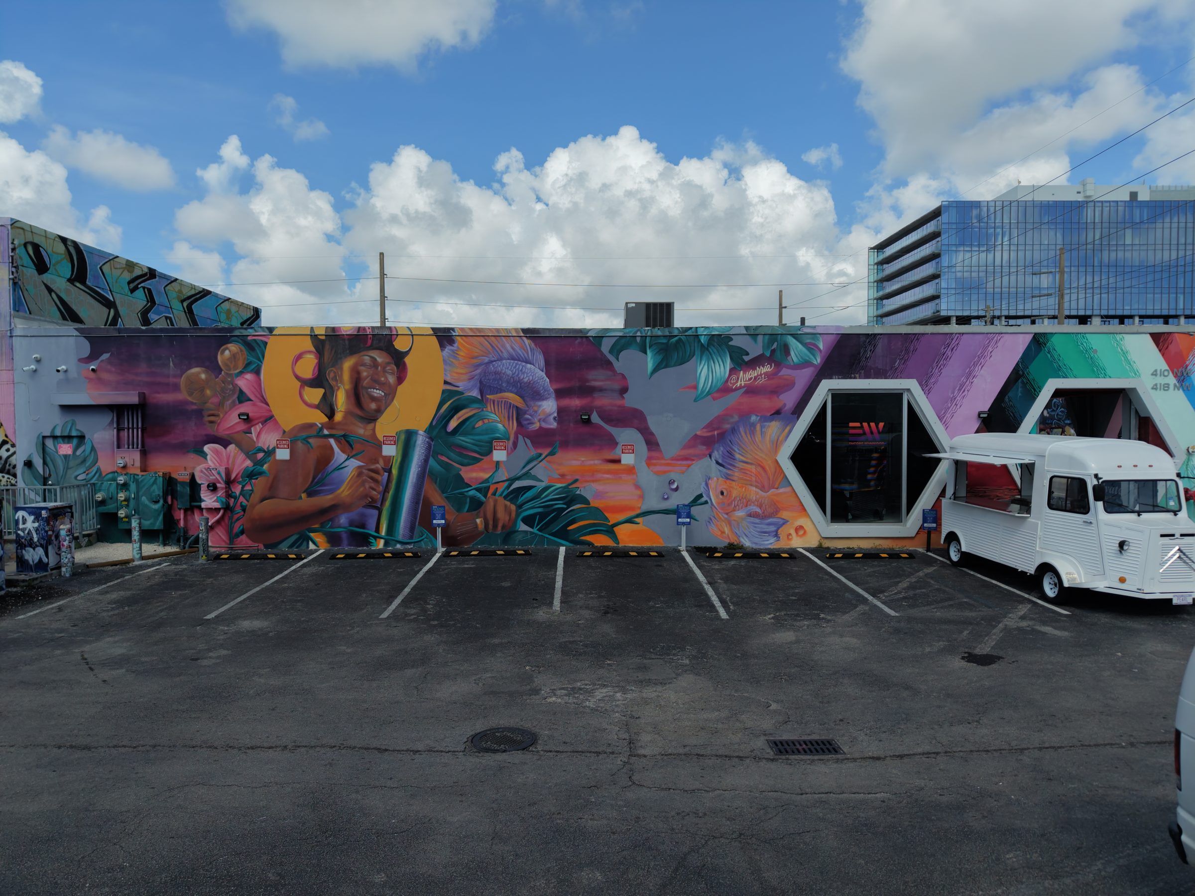 The private lot at Encore Wynwood from street level with a branded vehicle and the mural wall behind